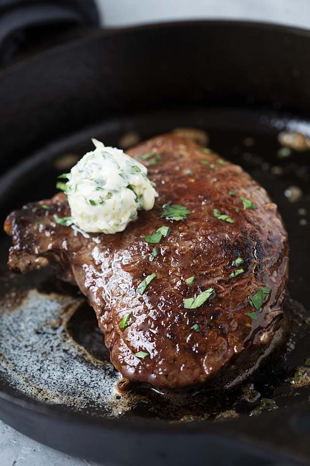 Steak cooked in a cast-iron skillet, topped with compound garlic butter.