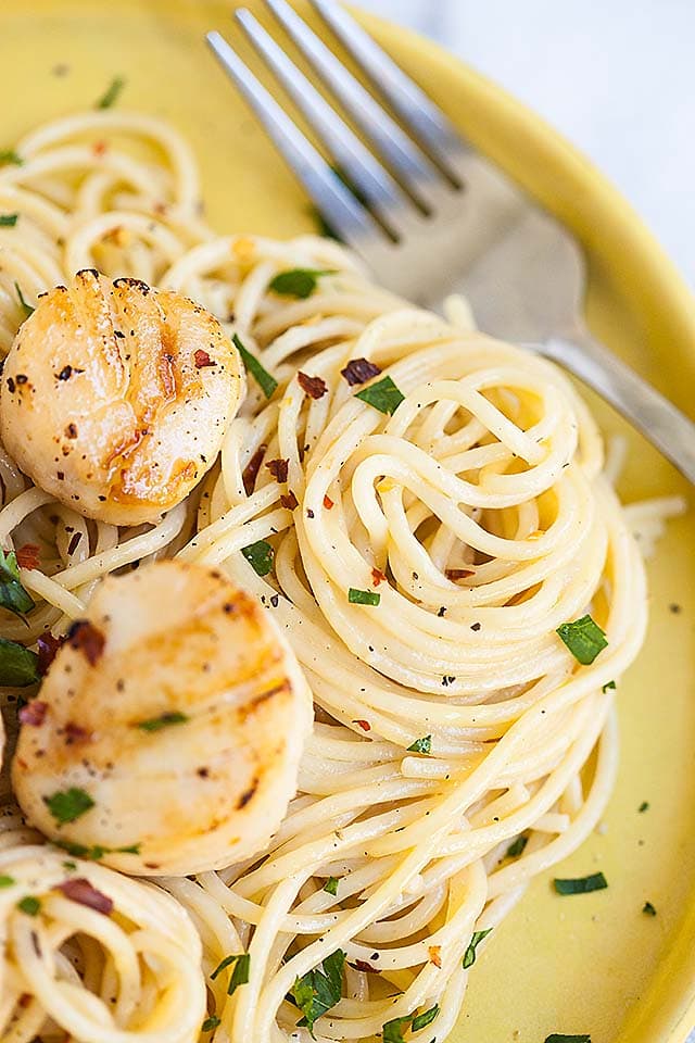 Easy homemade white wine spaghetti pasta with two scallops, with a fork, ready to serve.