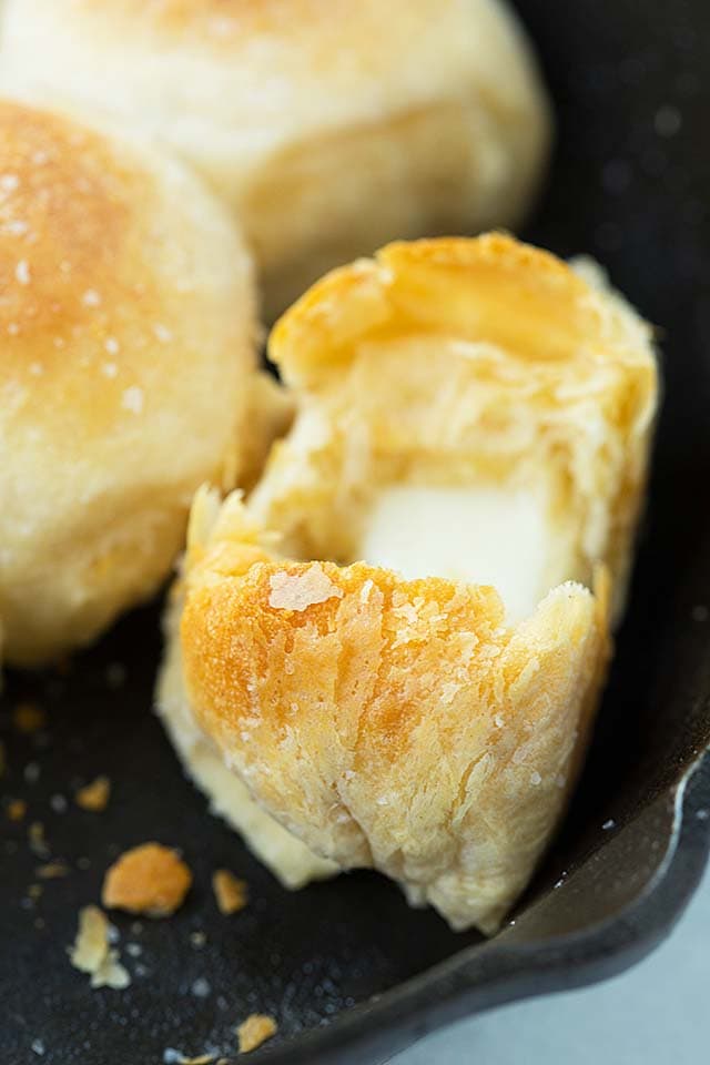 Flaky biscuits with melted mozzarella cheese in half on a skillet.