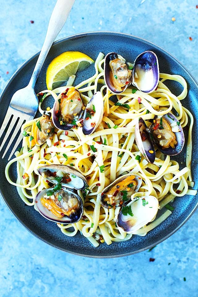 Clam linguine pasta with a lemon wedge on a plate, ready to be served.