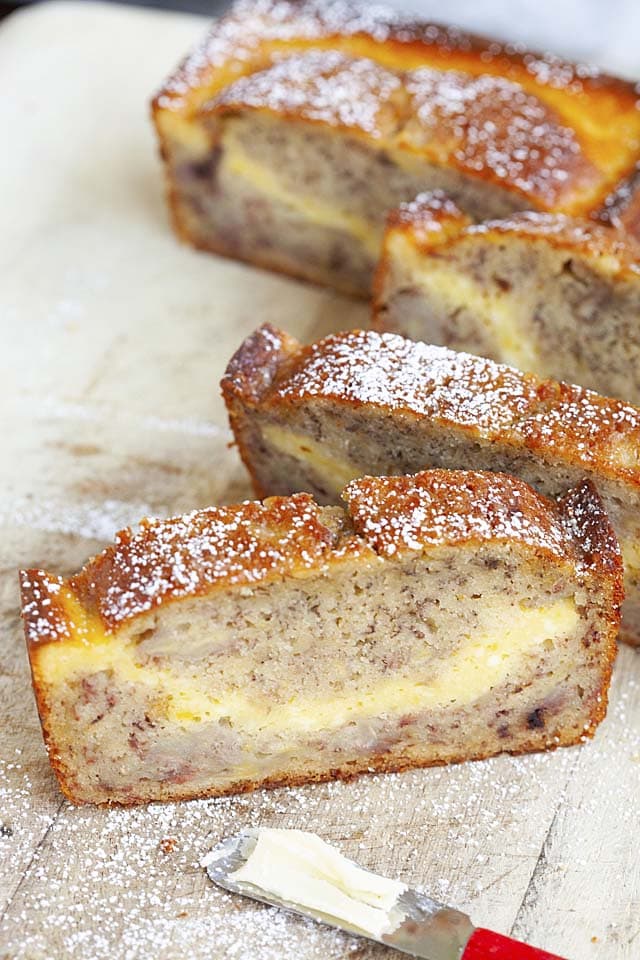 A slice of cream cheese filled banana bread, topped with powdered sugar.