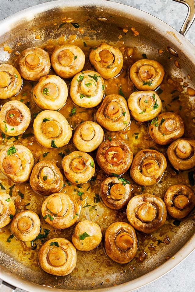 Sauteed mushrooms with minced garlic and butter in a skillet.