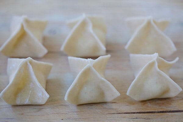 Wrapping crab rangoon with a wonton wrapper into the shape of little purses.