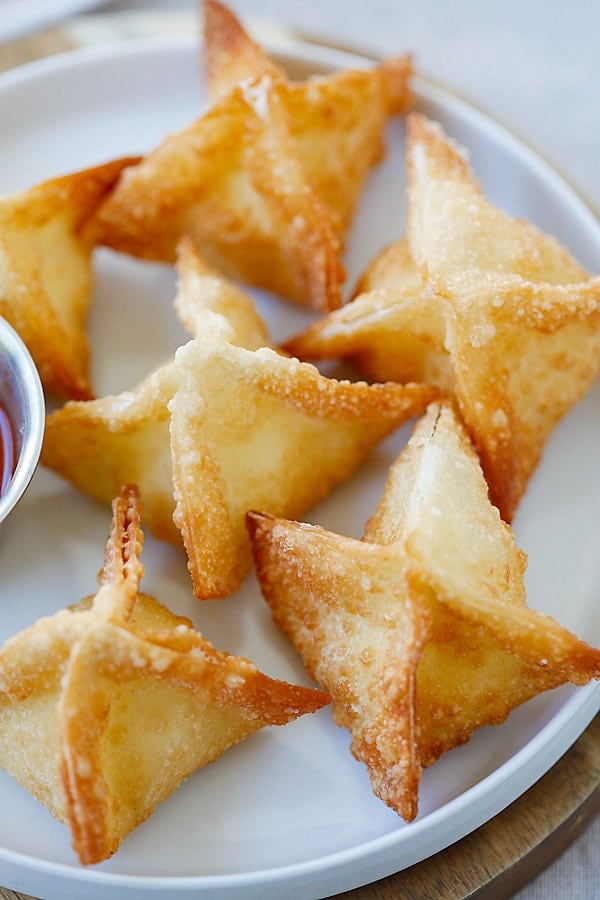 Crispy crab rangoon with crab rangoon dip on a plate.