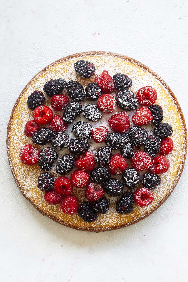 Top down picture of French yogurt cake, dusted with powdered sugar and topped with blackberries and raspberries.