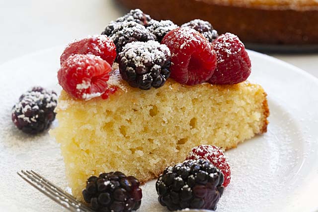 A piece of French yogurt cake with fork on a plate, ready to be served.