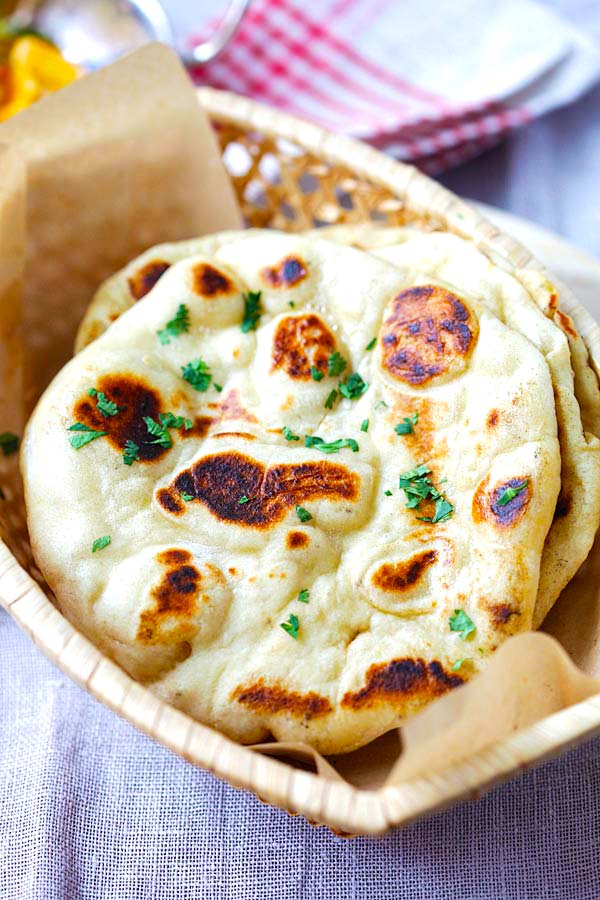 Naan with brown blisters served in a bread basket. 