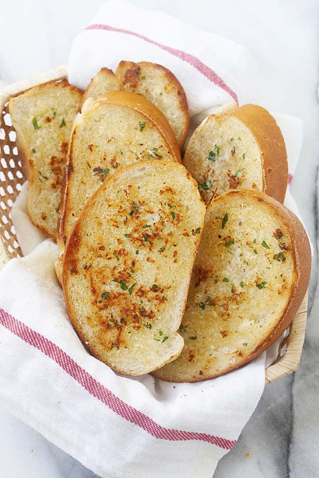  Frisch zubereitetes Knoblauchbrot in der Pfanne auf einem Korb, servierfertig.