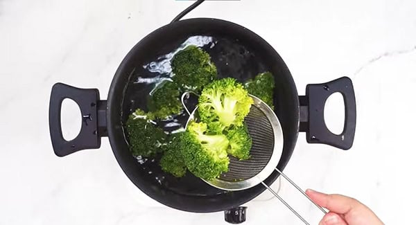 Broccoli florets on a strainer.