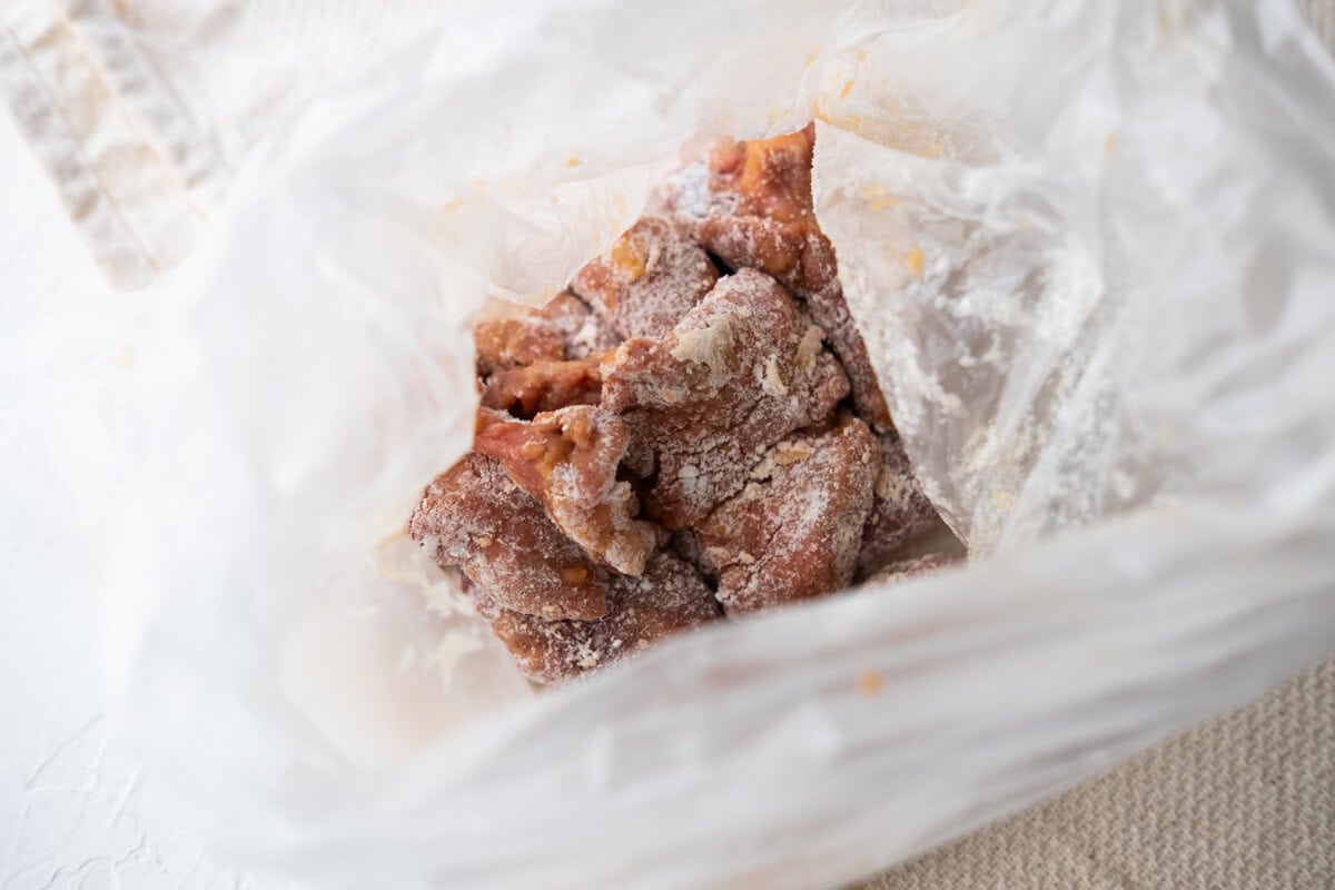 Coating the marinated beef with corn starch in a bag. 