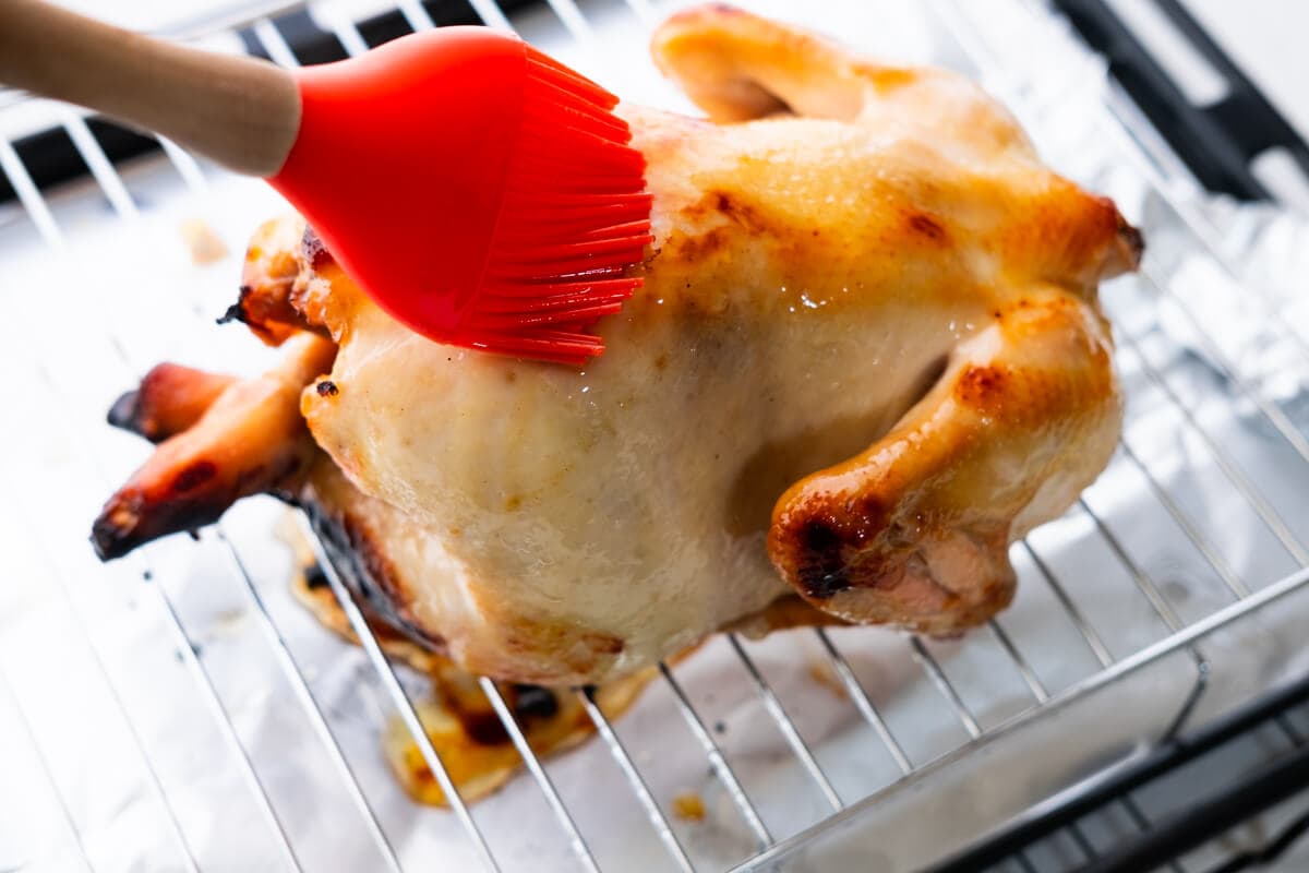 Brushing the whole chicken with the skin coating mixture. 