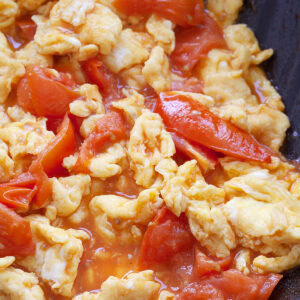 Tomato and eggs stir fried in a skillet.