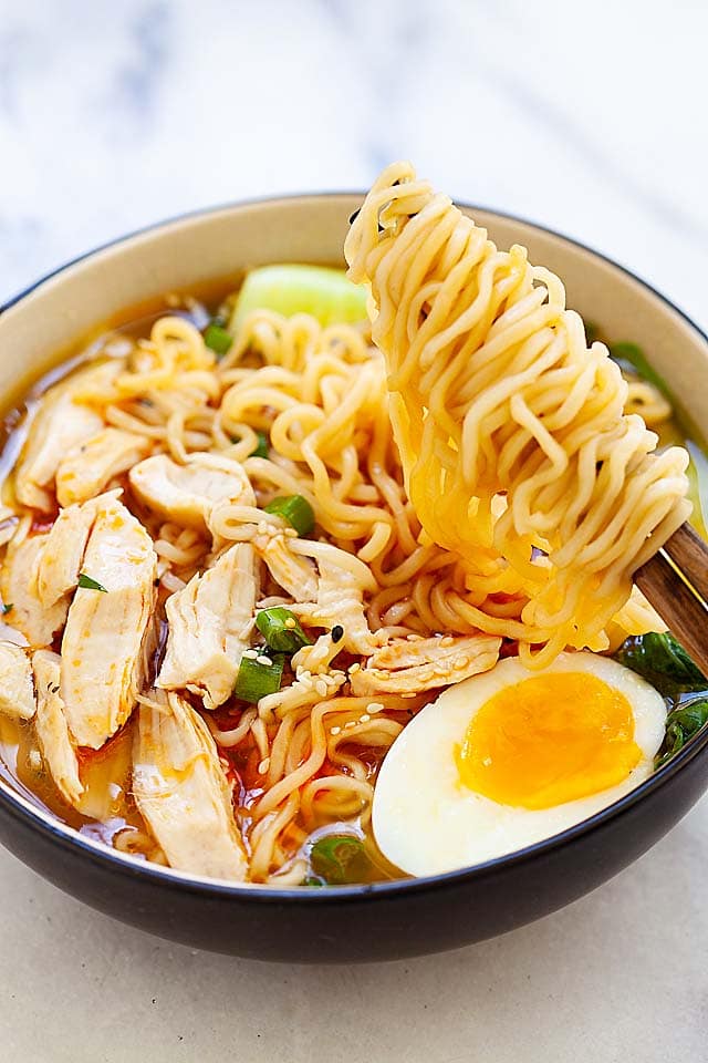 A pair of wooden chopsticks picking up ramen noodles made in an Instant Pot.