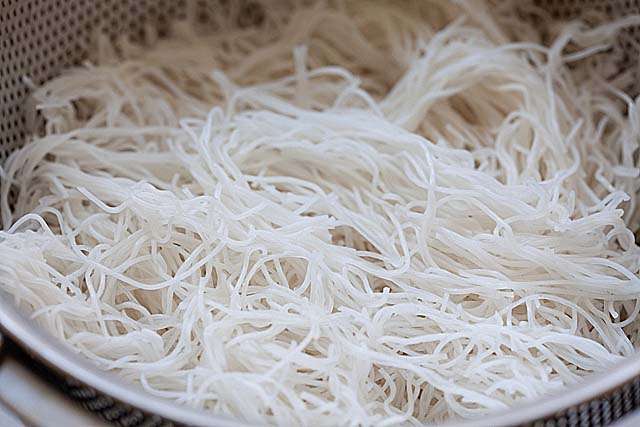 Rice sticks in a colander, ready for stir-frying.