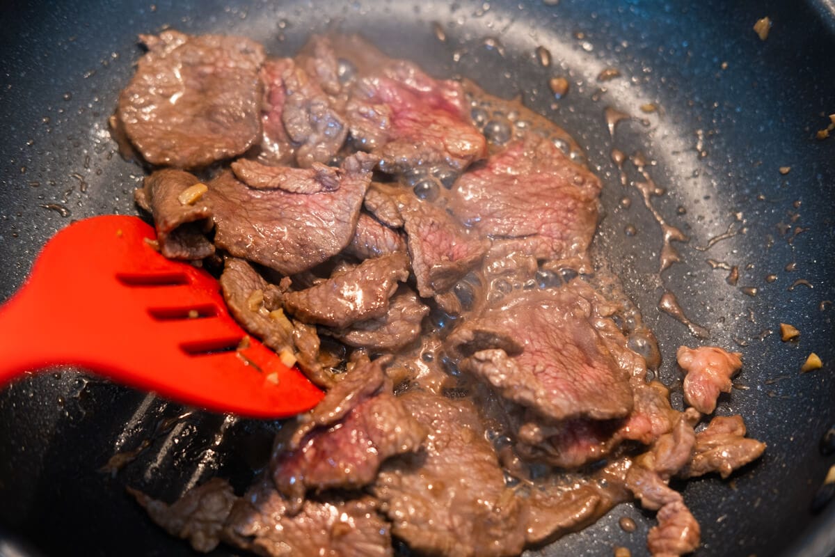 Stir-fry the marinated beef slices in a pan. 