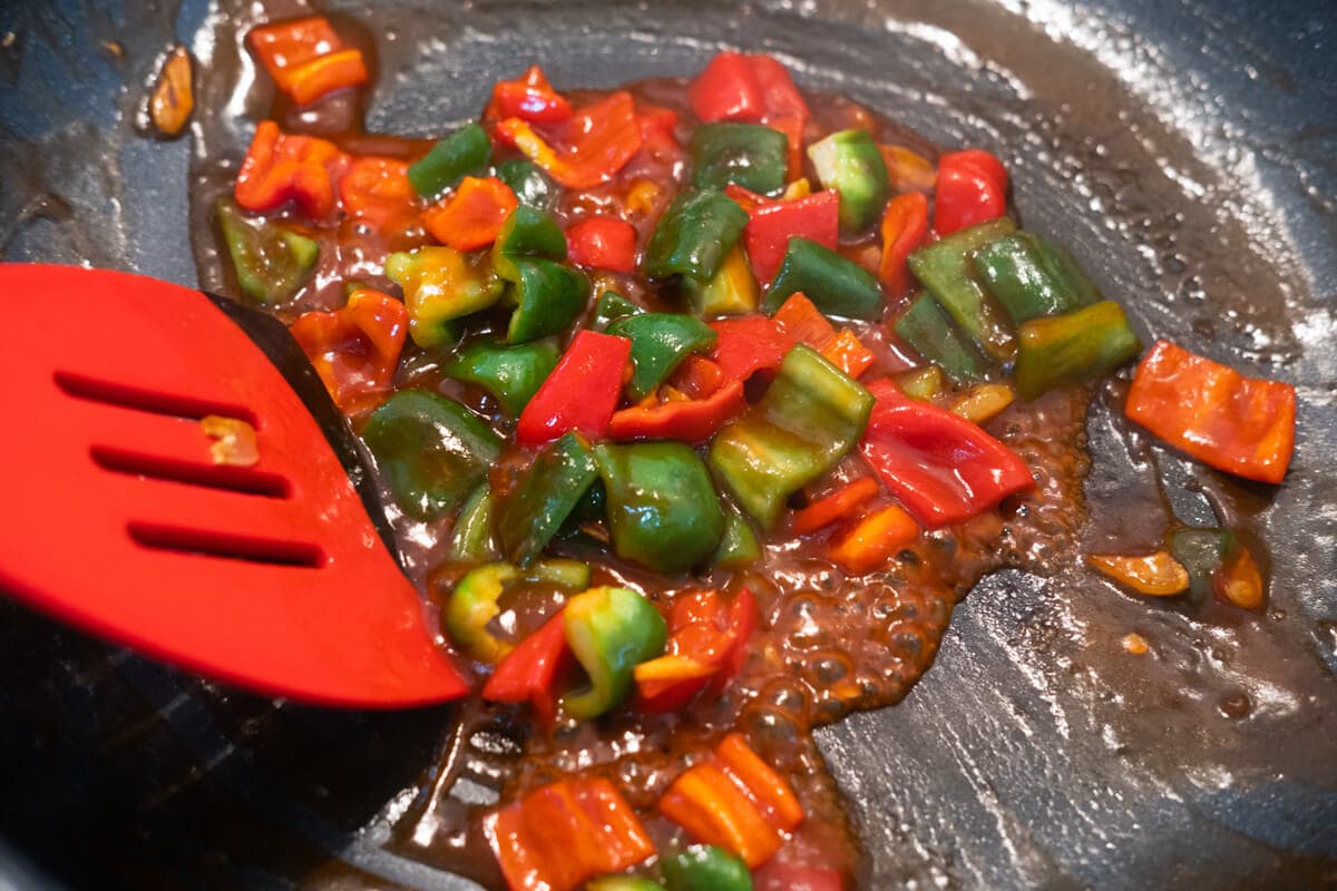 Sweet and sour sauce with green and red bell peppers in a pan. 