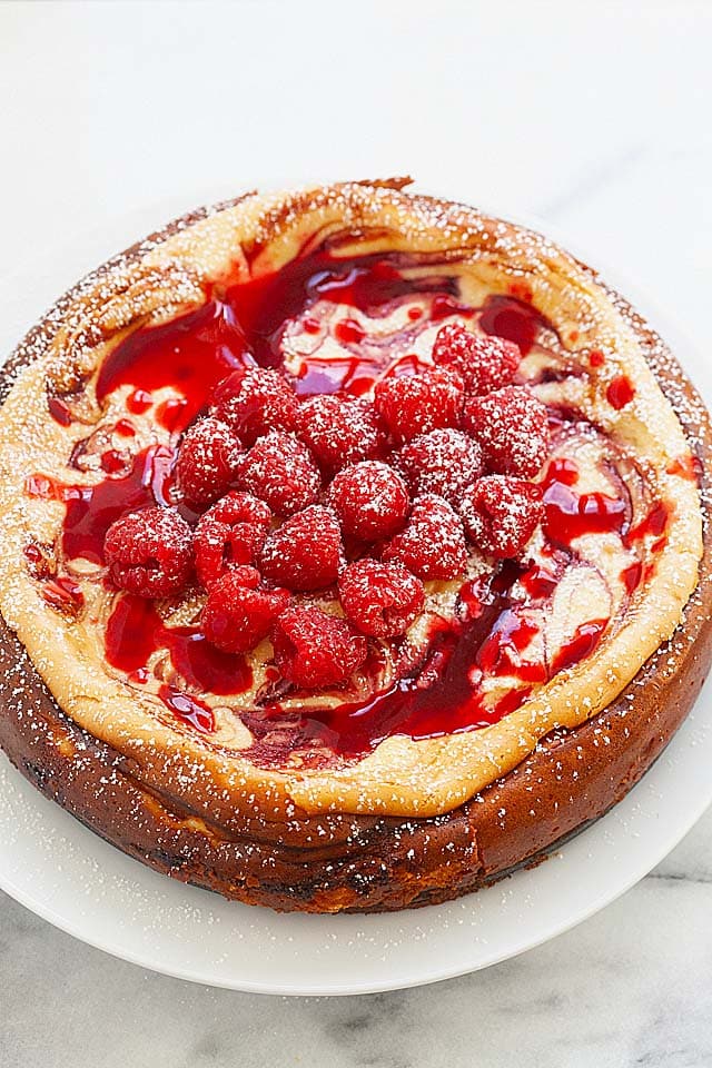 Fresh raspberry cheesecake with white chocolate, topped with raspberry sauce and fresh raspberries.