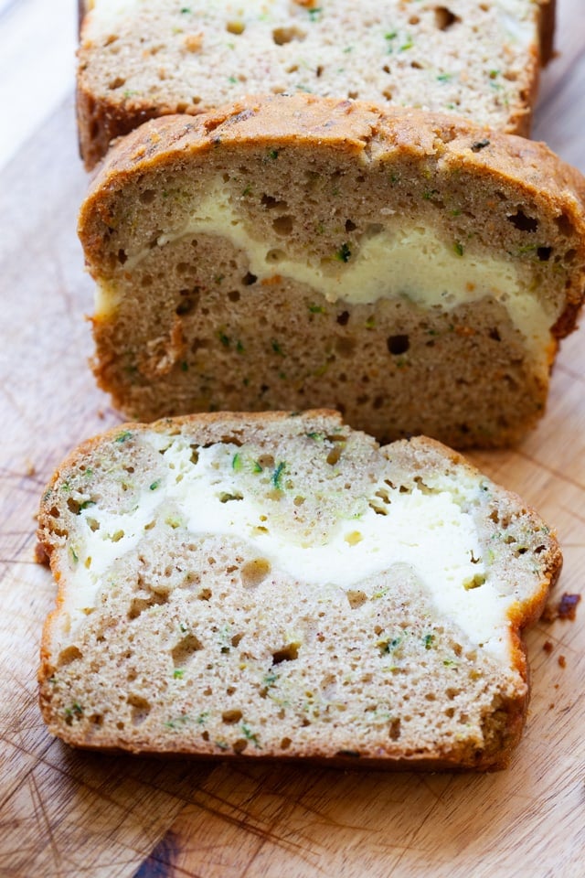A sliced loaf of zucchini bread baked with a ribbon of cheesecake filling.