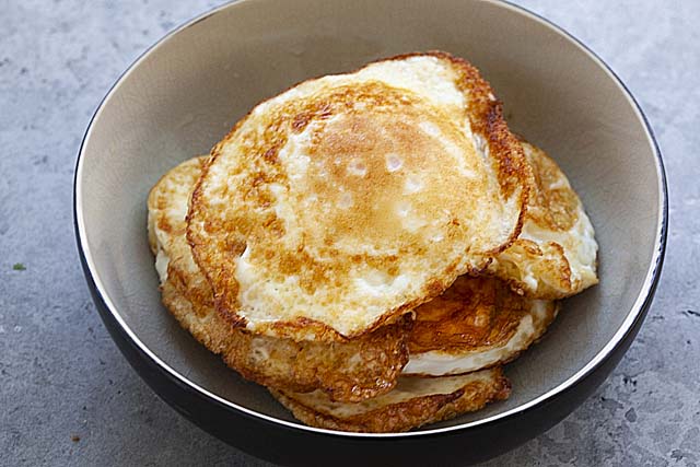 Four fried eggs in a bowl.