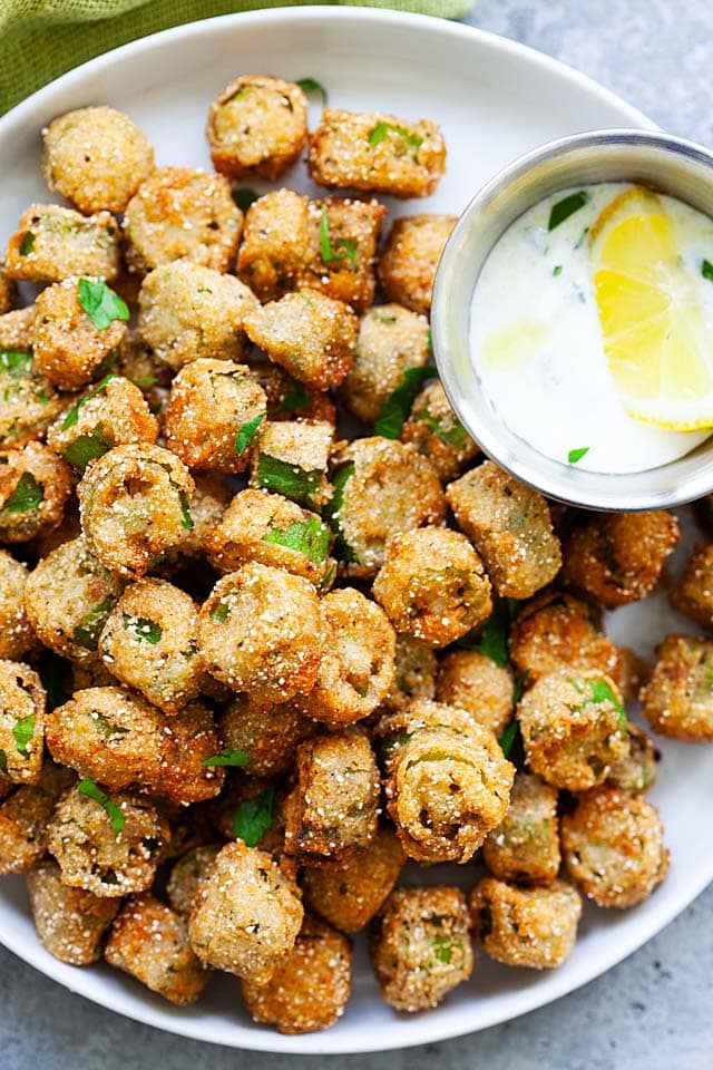 Deep fried okra with Ranch dipping sauce on a plate.