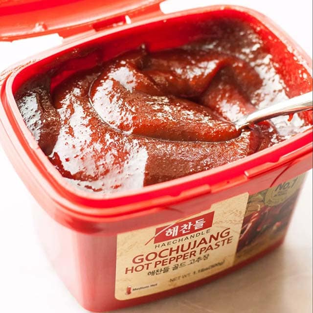 Gochujang in a plastic tub, used as a sauce for spicy Korean chicken wings.