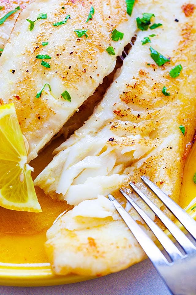 A fork poking through a cooked swai fish fillet.