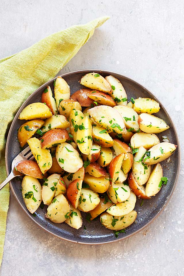 Patate bollite con prezzemolo, burro, sale e pepe nero, pronte da servire.