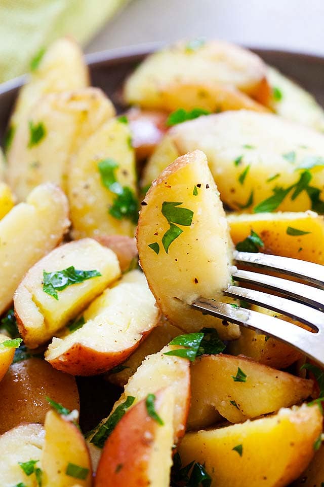 Pommes de terre bouillies avec persil, beurre, sel et poivre noir, prêtes à servir.