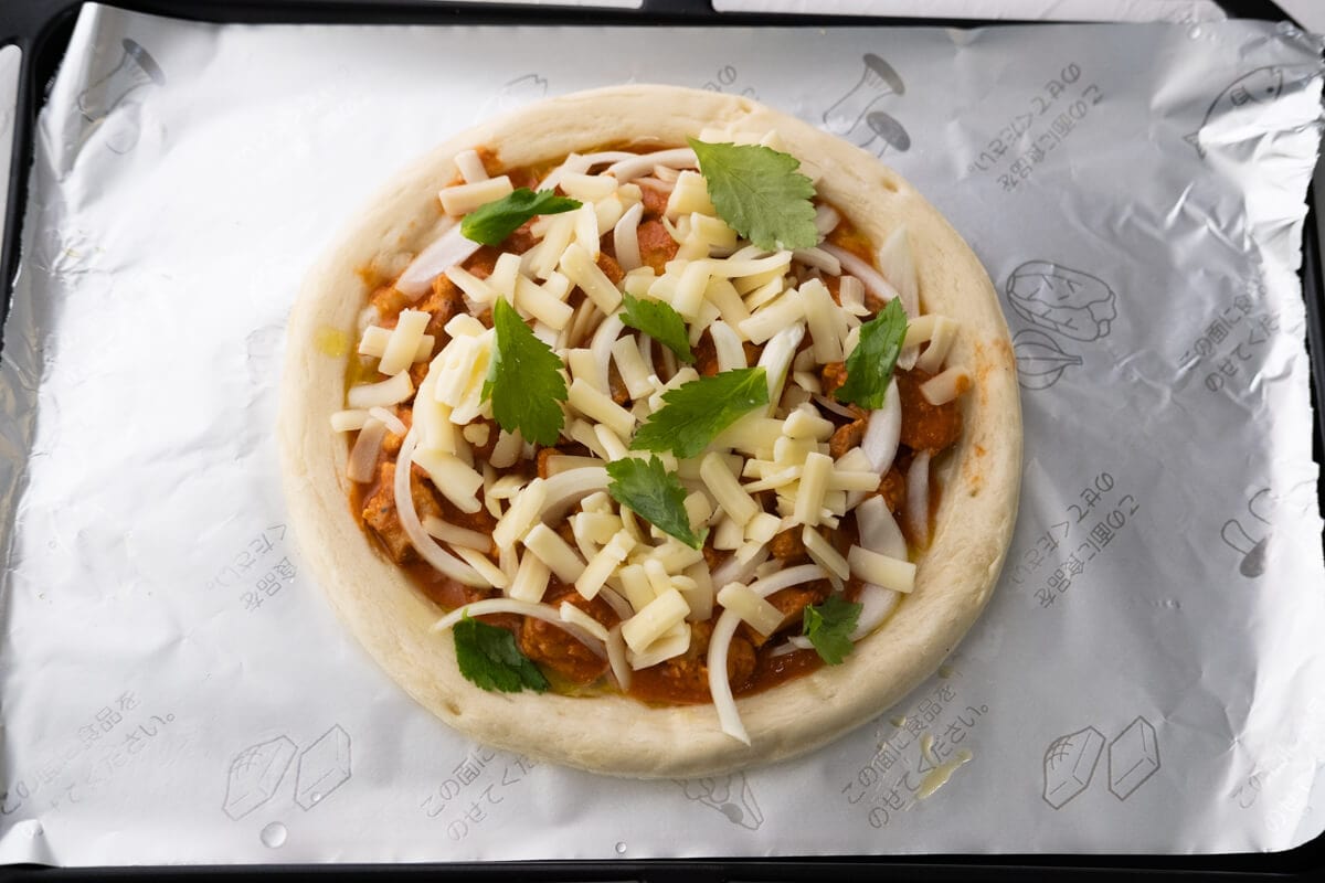 Indian pizza topping with cheese on a pizza crust.