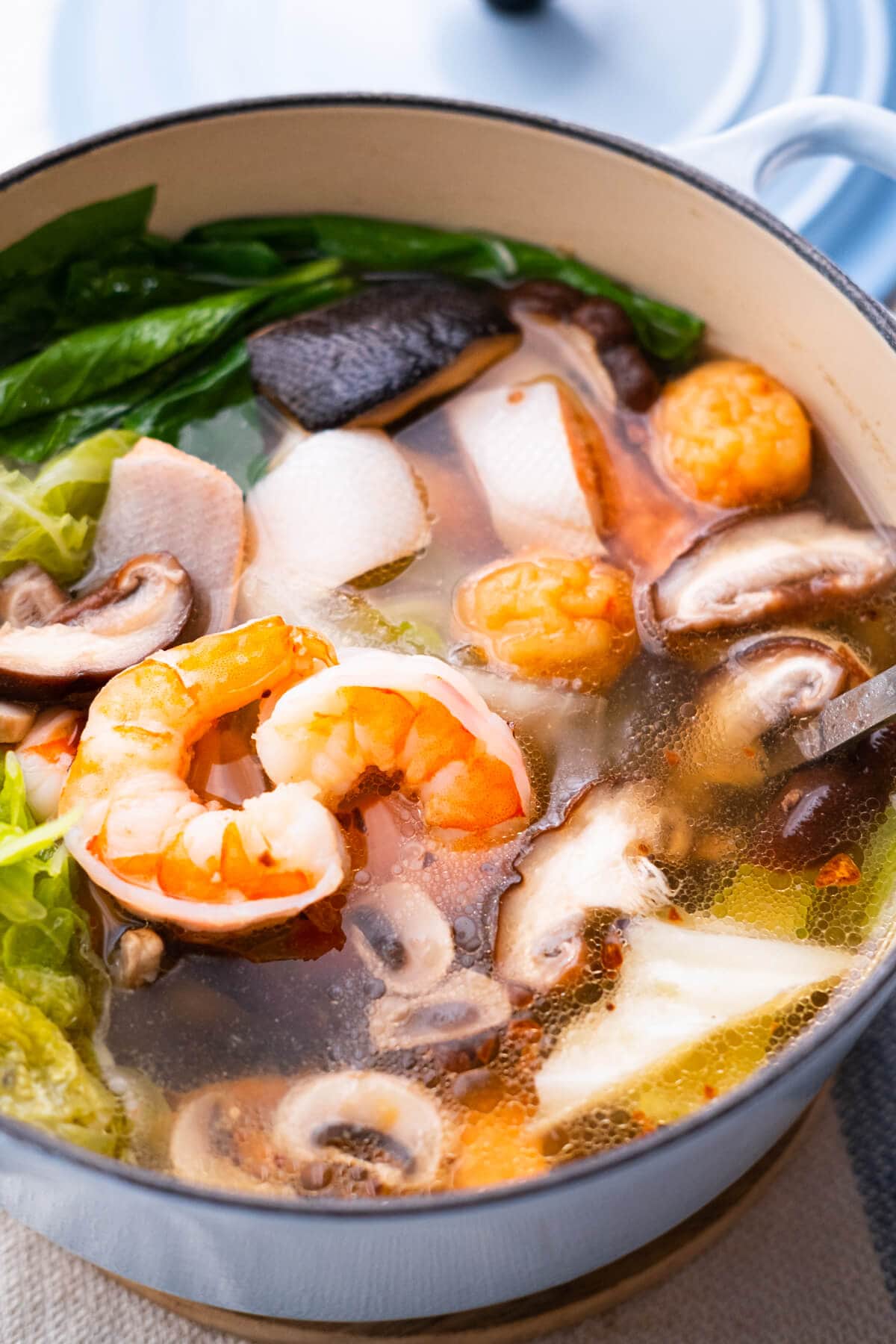 Chinese steamboat soup with a variety of fresh ingredients in a simmering pot of soup stock.