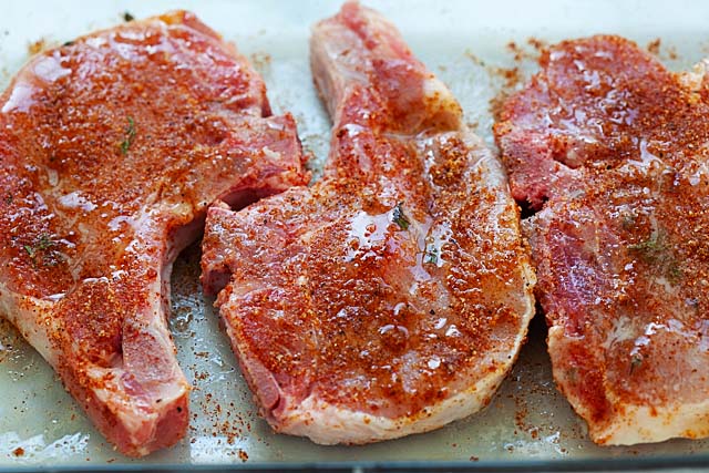 How to bake pork chops? Baked pork chops recipe with seasonings and marinade on a baking tray.
