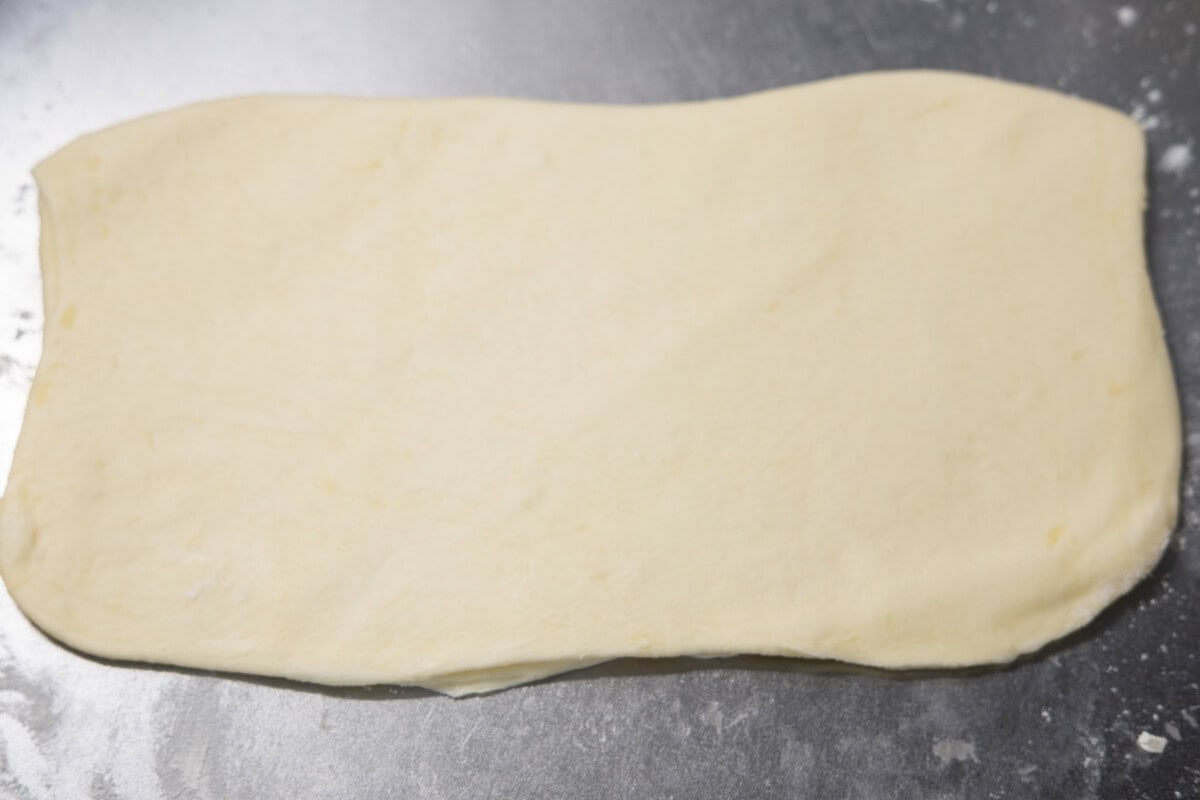 Puff pastry dough is rolled out into a rectangular shape. 
