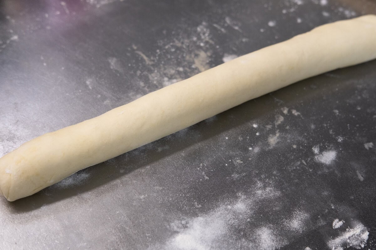 Egg tart dough is rolled up into a tight log. 