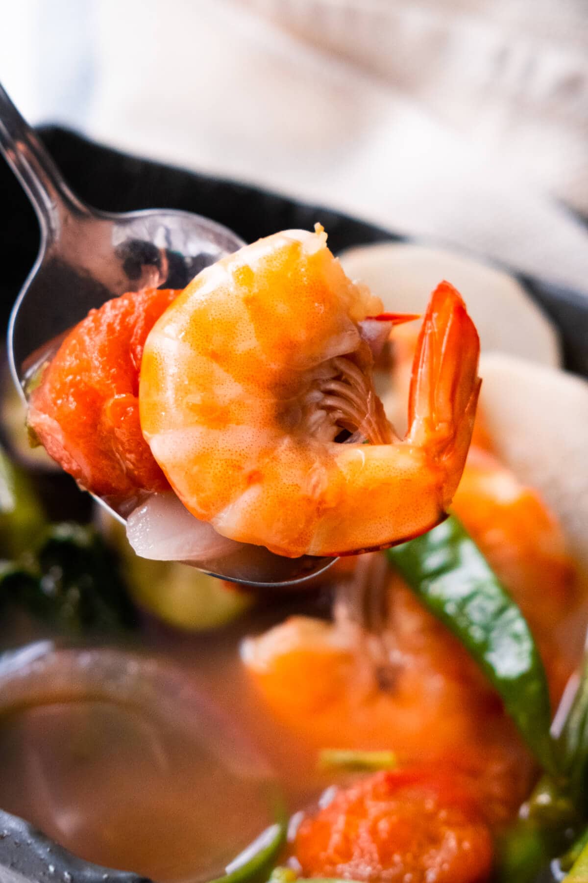 Shrimp and tomato are scooped with a spoon from this delicious shrimp sinigang stew.