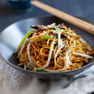 Vegetable chow mein with mushrooms and mixed vegetables in a bowl.