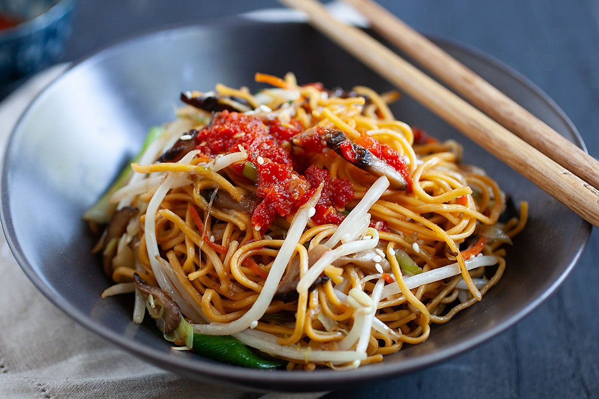 Vegetable chow mein served in a bowl with a pair of chopsticks. 