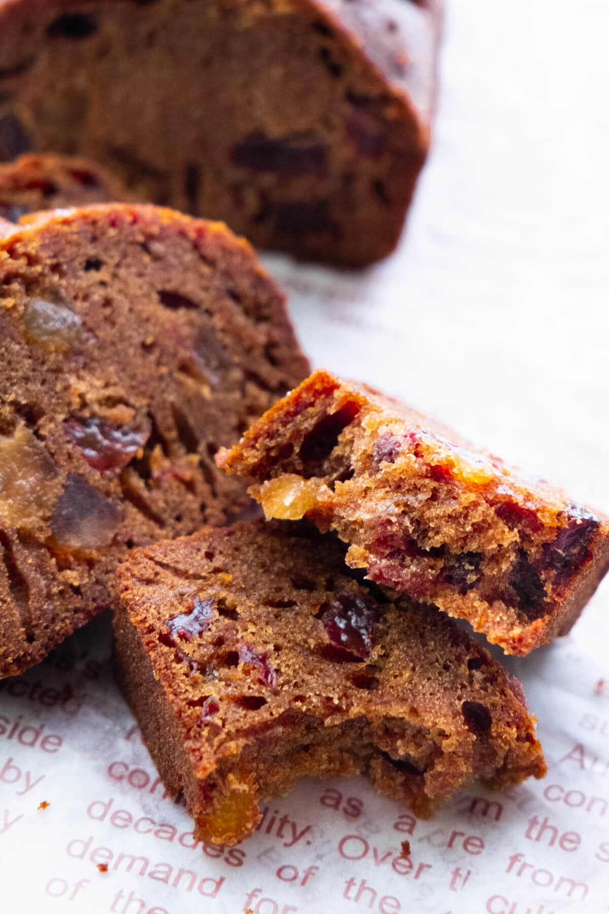 A slice of Christmas fruit cake torn in half, showing the dried fruits and moist texture.