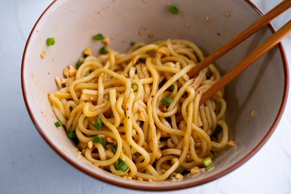 Toss the noodles with the sauce and top with ground peanuts and scallion. 