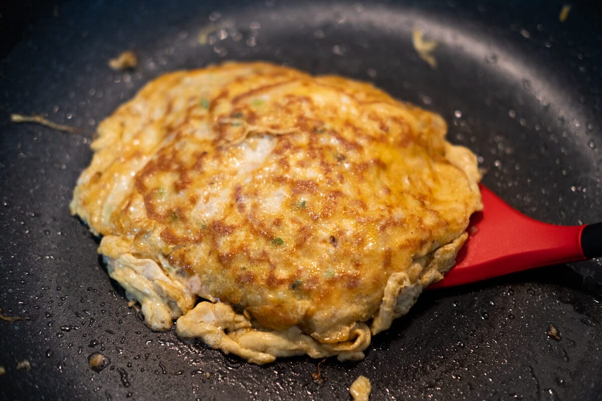 Flipping Chinese-style omelet with a spatula.