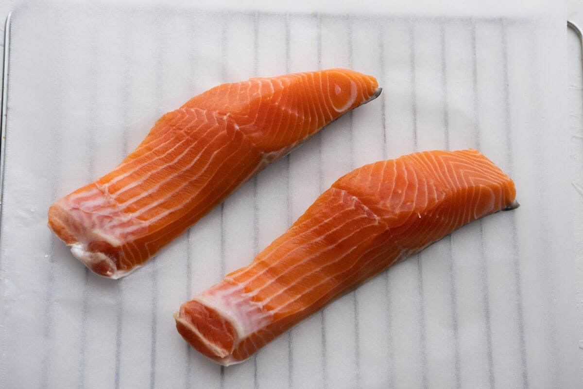 Put the salmon fillets skin down on a parchment paper lined baking sheet. 