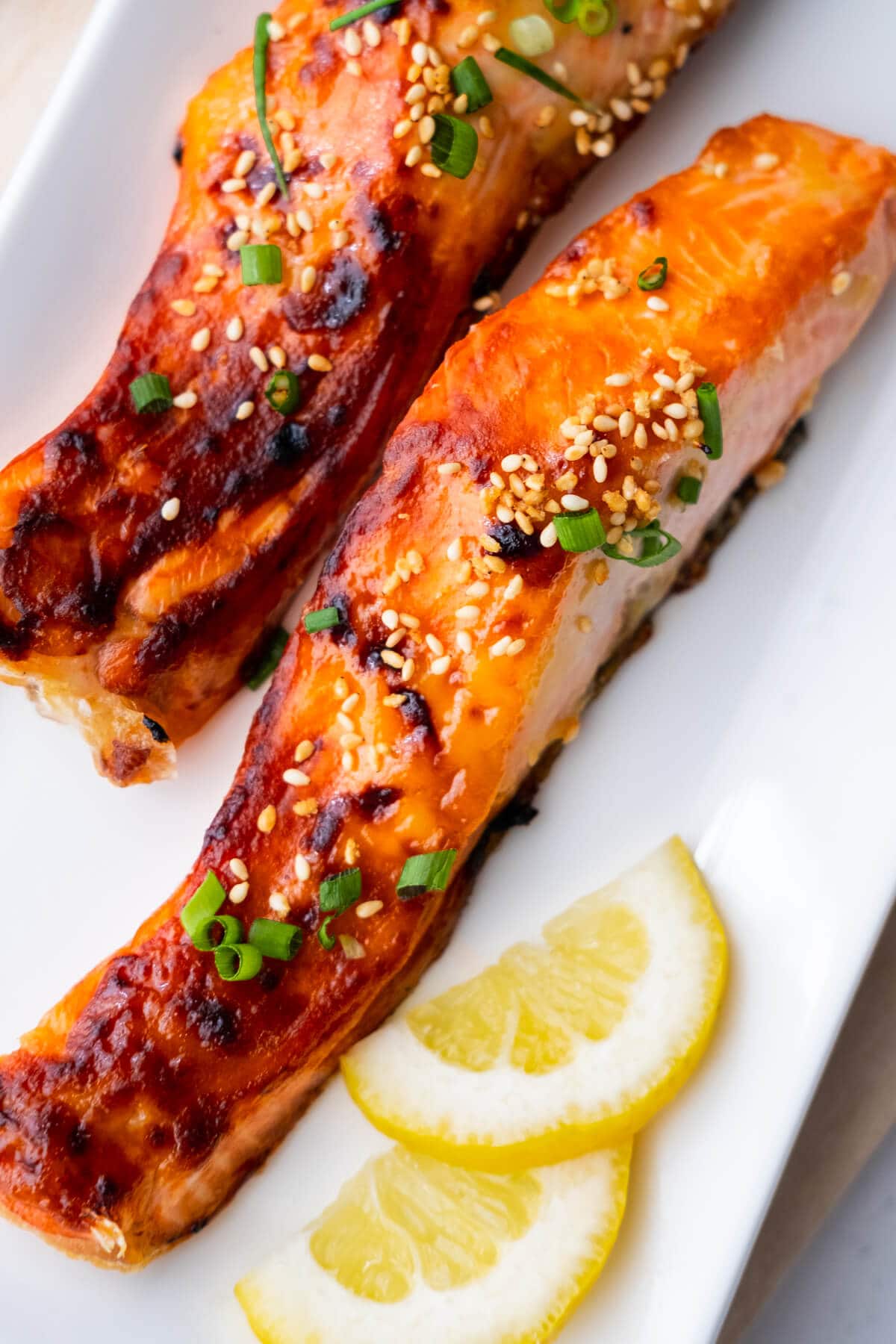 Japanese miso-glazed broiled salmon garnished with chopped scallions in a wooden serving dish.