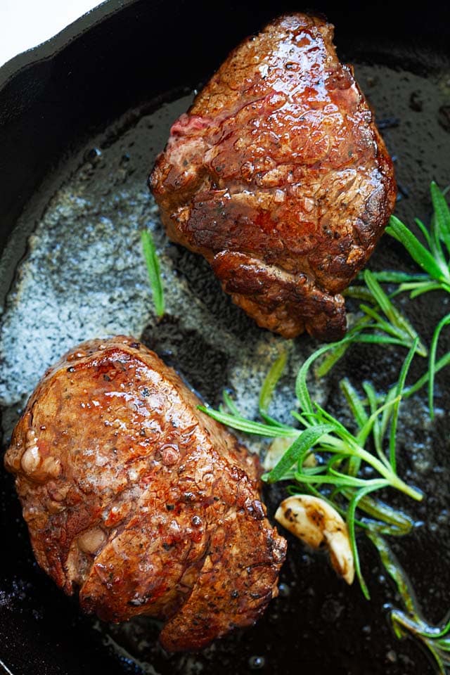 Filet mignon recipe with butter, garlic and rosemary, cooked on a skillet on stove top.