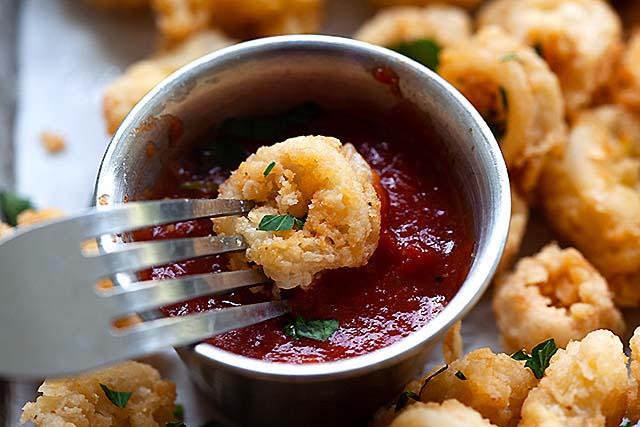 Um pedaço de calamares fritos mergulhados em molho de calamares fritos.