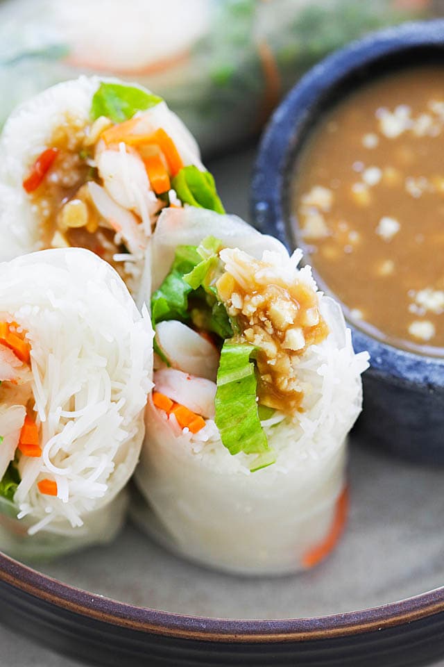 Summer rolls, cut into half and served in a plate with peanut dipping sauce.