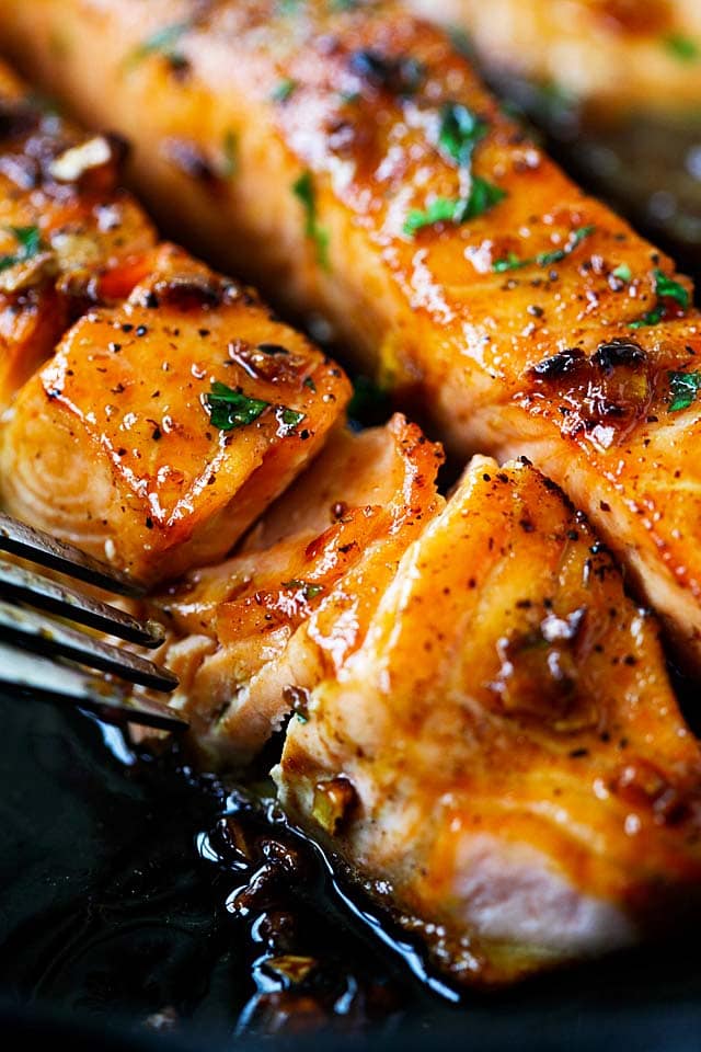 Close up of salmon with honey garlic sauce on a skillet.