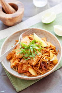 Mee goreng with squid, potatoes and bean curd, topped with lime wedges.