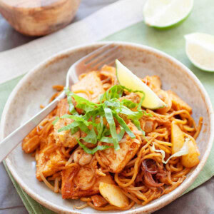 Mee goreng with squid, potatoes and bean curd, topped with lime wedges.