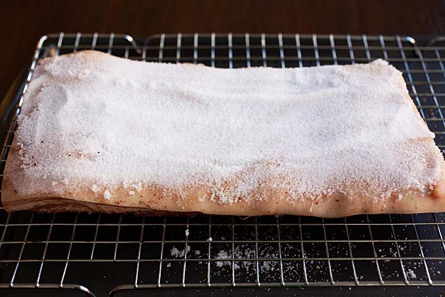 Adding salt to to the skin of pork belly.