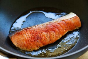 Cooking salmon in a pan on the stove.