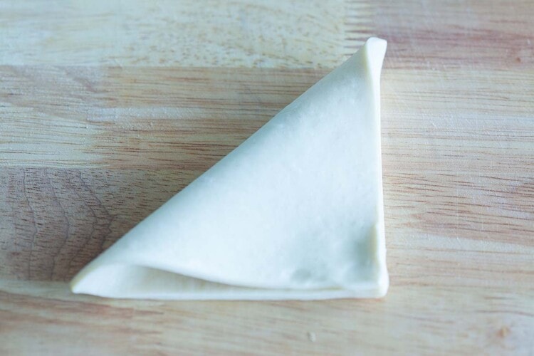 Folding puff pastry into a triangle.